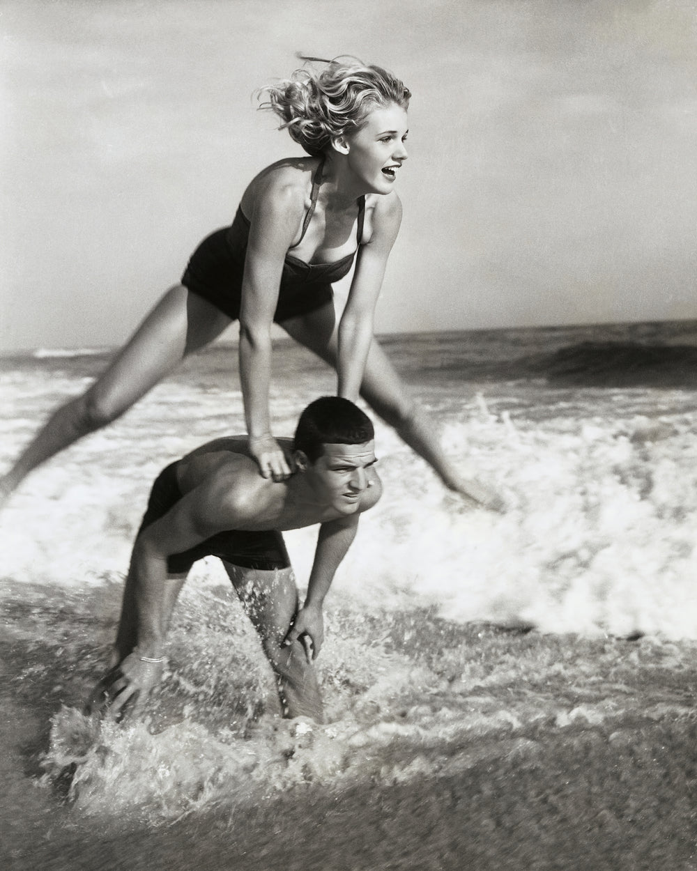 Young Couple Playing Leapfrog in Surf