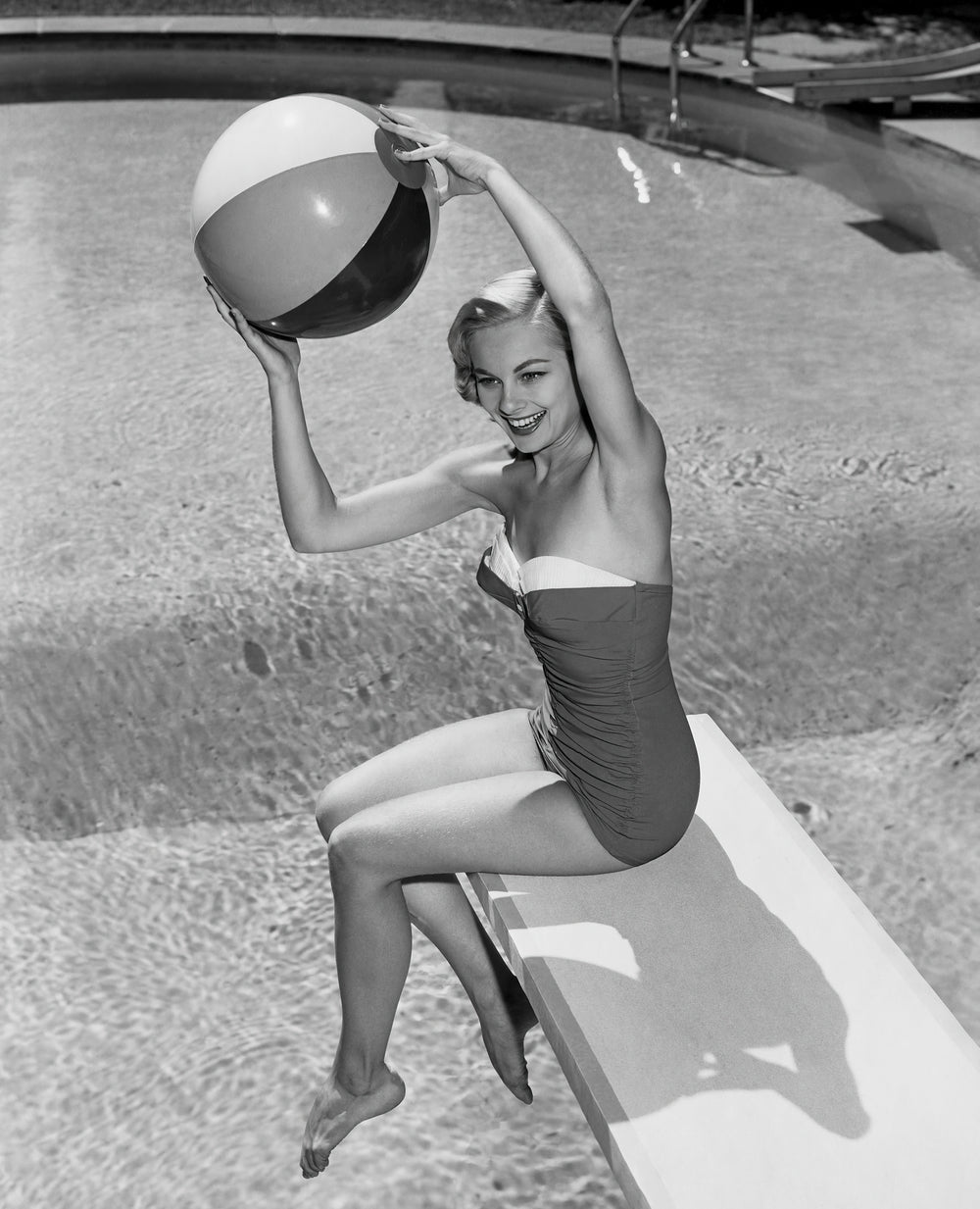 High Angle View of Young Woman Sitting on Diving Board Throwing Beach Ba